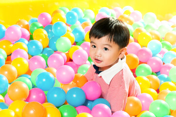 Fototapeta na wymiar Young child playing in balls pit at indoor playground