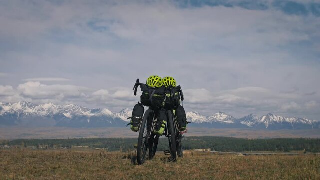 The mixed terrain cycle touring bike with bikepacking. The travel journey with light bicycle bags designed or modified for cycling. The trip on multitrack bike, outdoor road in mountain snow capped.