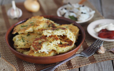 Home cooking potato pancakes or potato pancakes.The national dish of Belarus, Ukraine and Russia. On a wooden background, potato pancakes surrounded by sauce, salted fish and spices.
