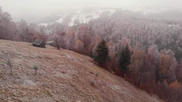 Aerial view of wintertime scene in the Transylvanian village, Pestera, with white frost, fresh snow, blizzard, and fog, at the foot of the Carpathian Mountains