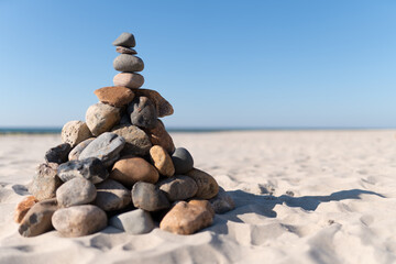 Pyramide aus Steinen am Strand vor dem Hintergrund von Meereswellen und  Sandstand auf dem Darß bei Prerow an der Ostsee