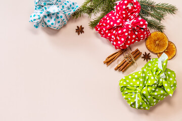 Christmas gifts furoshiki on pink background. Eco christmas holiday concept. Flat lay top view. Copy space.