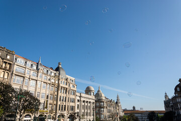 Fototapeta na wymiar Porto, Portugal - 08/28/2019: Big soap bubbles and Porto city in the background. Aliados Avenue.