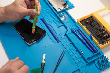 Repairman workplace. Technician holding screwdriver and repairing smartphone. close-up. selective focus