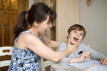 Fototapeta premium A mother is definitely fighting with her first-grader son. They are forced to do isolation tasks due to the coronavirus pandemic.