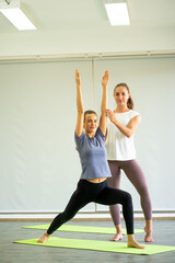 Naklejka na ściany i meble Caucasian healthy woman practicing Yoga exercise on green mat with teacher 