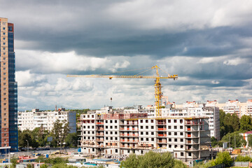 Construction crane on construction site in city on cloudy sky background