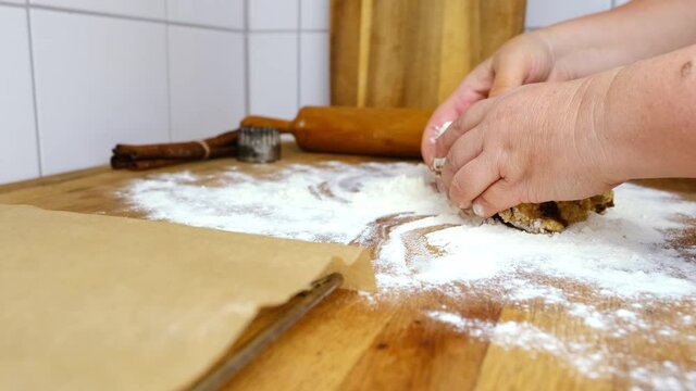 woman prepares butter cookies at home in the kitchen, the table is sprinkled with flour, rolls out the dough, cuts out the shape, the concept of cooking festive food, christmas sweets