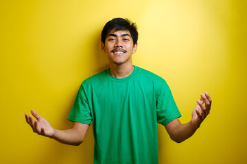 Young Asian Man in Green T-shirt Smiling and Shows Asian Greeting Gesture