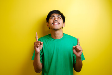 Asian young man in green t-shirt looked happy thinking and looking up, having good idea