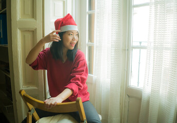 lifestyle home portrait of young beautiful and happy Asian Korean woman in Santa Claus hat and red jersey enjoying Christmas time smiling cheerful