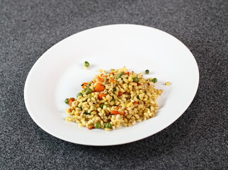 Cooked pearl barley with carrot and green peas on plate