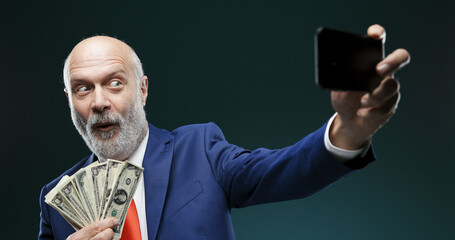 Businessman taking a selfie while holding cash money