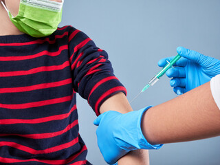 Boy wearing a surgical mask being vaccinated