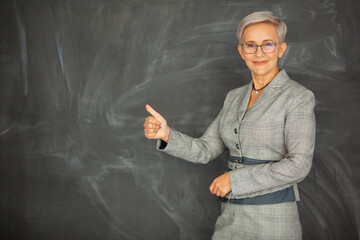 beautiful adult woman in suit near blackboard