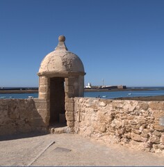 Fototapeta premium Sentry box in the Castle of Santa Catalina, Cadiz, in the background the Castle of San Sebastian and its lighthouse