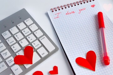 flat lay valentine's day in the office. Red heart on white keyboard and table, diary with the words "I love you"