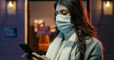 Woman wearing a surgical mask and connecting with her phone