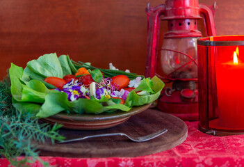 new Year's still life with salad of tomato, cheese, green onions and tricolor violet flowers, and a candle