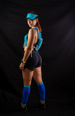 Beautiful redhead girl in jogging uniform posing in studio on black background
