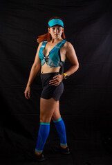 Beautiful redhead girl in jogging uniform posing in studio on black background