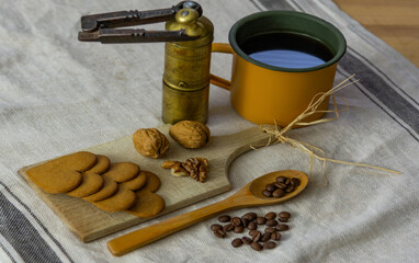 A cup of coffee, a coffee grinder, walnuts and cookies