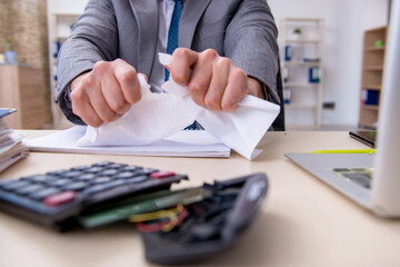Young male employee unhappy with excessive work in the office