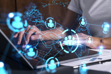 Businesswoman typing on laptop in office. Social network icon hologram. People connection concept....