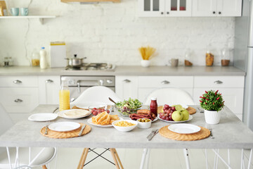 Bright kitchen. Latin style breakfast on the table. Modern bright white kitchen interior with wooden and white details
