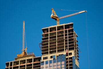 Cranes are building a skyscraper. Against the background of the blue sky.