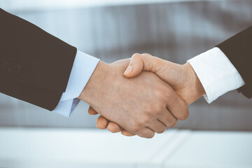Obraz premium Businessman and woman shaking hands in office. Concept of handshake as success symbol in business