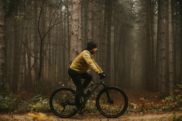Young man biking through autumn forest