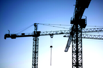 Fototapeta premium Two construction cranes. Evening cloudless sky.