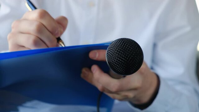 Correspondent or journalist interviewing and writing something down in a notebook