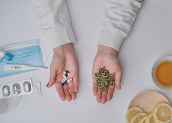 Medicine pills or herbs concept. Natural herbs. Two hands as a scale. Pandemic problem