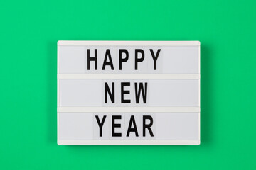 Happy new year text in a light box on green background