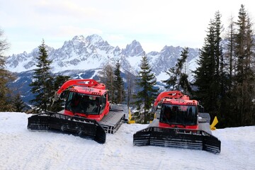 Two standing snow groomers next to ski slope on Monte Elmo/Helm. Croda Rossa peak in background. Dolomites, Italy, Puster Valley/Alta Pusteria, South Tyrol.