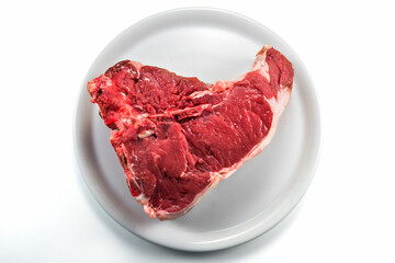 Raw T-bone steak on white round plate