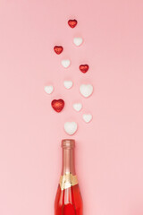 Bottle of wine and red white hearts on pink background. Valentines day concept. Flat lay, top view, copy space.