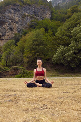 Naklejka na ściany i meble Yoga classes in nature. The concept of playing sports alone. Social exclusion. A woman does yoga in the mountains