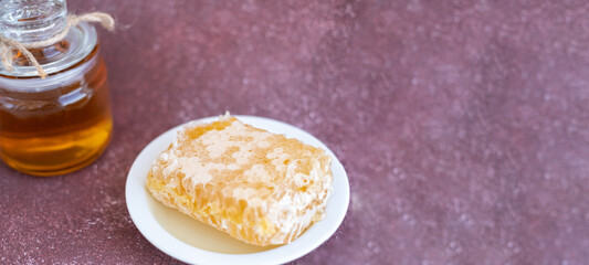 glass jar full of honey, plate with honeycomb