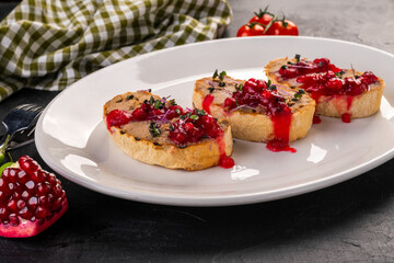 bruschetta with pate and lingonberry sauce. Toasts with pate for the restaurant menu on a white plate and a dark background