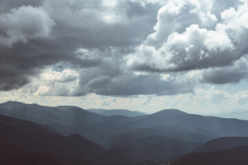Obraz premium Thick clouds over mountain range, hills in blue haze