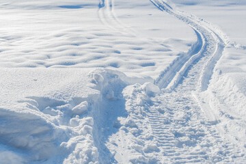 Snowmobile tracks in deep snow. Twisting traces of a snowmobile crossing snow covered field - 397641929