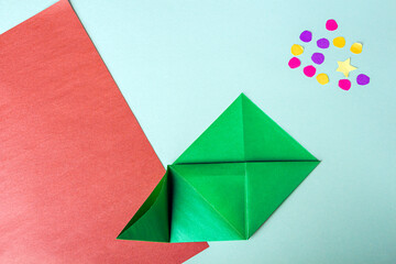 Concept of DIY and kid's creativity, origami. Step by step instruction: how to make bookmark as christmas tree. Step 6 Bend left corner up, and turning down its upper part inward. 