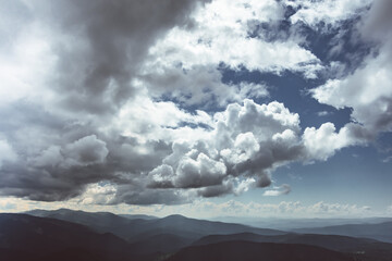 Thick clouds over mountain range, hills in blue haze