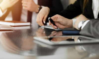Unknown businessman shaking hands with his colleague or partner above the desk in sunny office, close-up