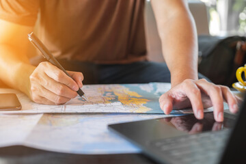 Traveler is planning vacation using the world map. Man is writing notes and pointing on the map...