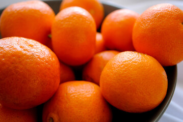 Ripe juicy tangerines in a deep ceramic plate.