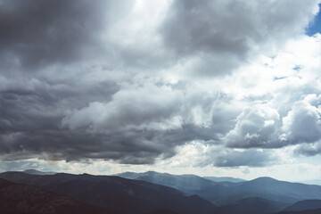 Fototapeta na wymiar Thick clouds over mountain range, hills in blue haze